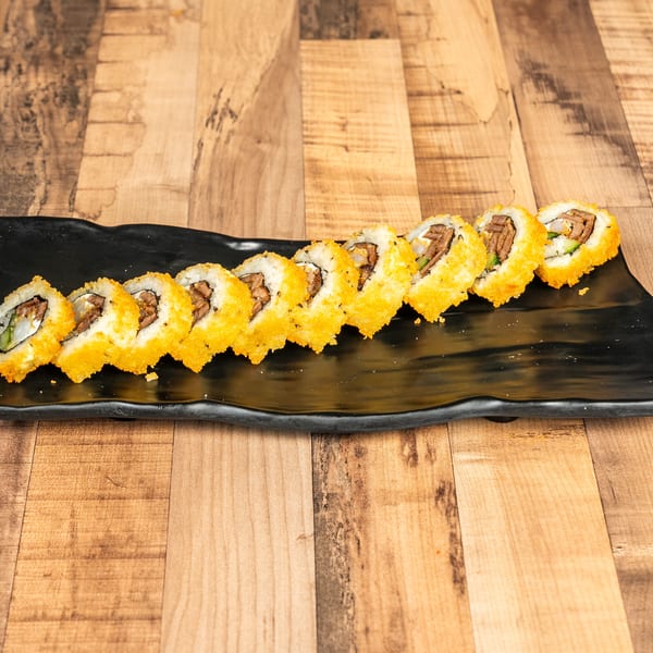Ten pieces of sushi with beef, cream cheese, and cucumber, topped with orange roe on a black plate.