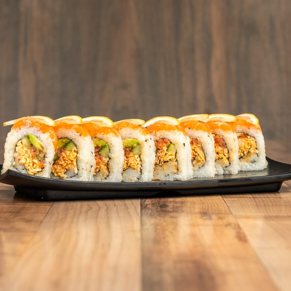 A row of sushi rolls with salmon and lemon slices on top, on a black rectangular plate.